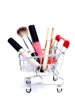 Shopping cart with cosmetics on white background