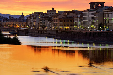 Fototapeta premium a blurred canoe at sunset on the river arno in florence, italy