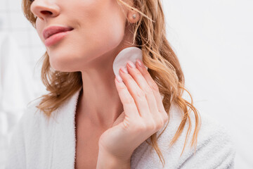 cropped view of woman applying toner with cotton pad on neck
