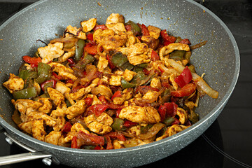 Pollo guisado con verduras en la sartén.