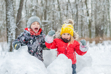 Boy and girl laughing in snow forest.
