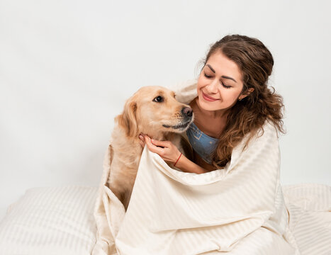 Female woman girl hugging with her labrador retriever dog wrapped n a white blanket. Romantic relationship human and dog concept