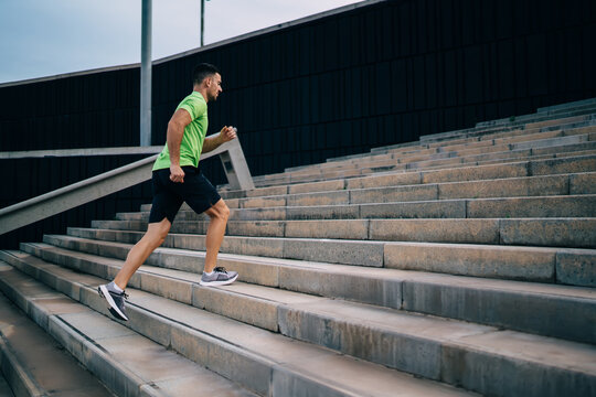 Caucasian male jogger have effort cardio training at urban settings feeling energy and vitality for keeping perfect body shape, determined man running at stairs during morning physical workout