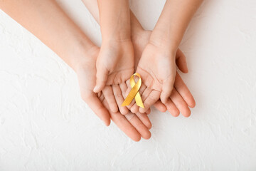 Hands with golden ribbon on white background. Childhood cancer awareness concept