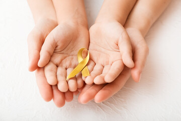 Hands with golden ribbon on white background. Childhood cancer awareness concept