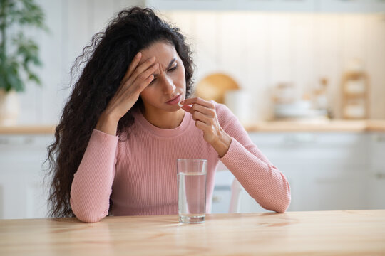 Young brunette woman suffering from headache or migraine at home
