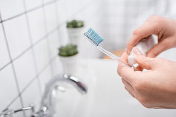 cropped view of woman holding toothbrush with toothpaste