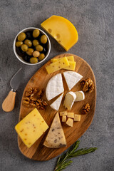 Assorted cheeses with nuts, olives and rosemary.