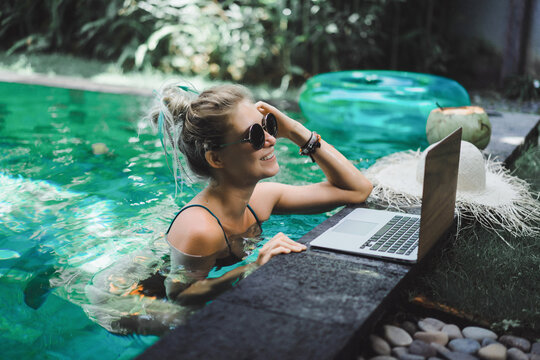 Freelancer girl working on vacation. .Young woman with laptop works while sitting on a sun lounger. Work from anywhere, freelance.