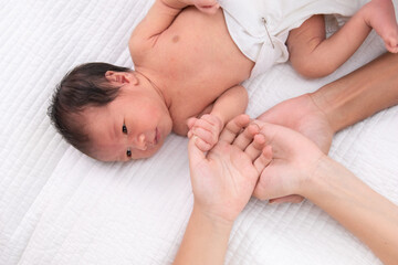 Beautiful shape hand of father, mother, daughter or sister hold tiny newborn hand on white bed with love, care and protection, infant look to mother face. baby hold his sister finger