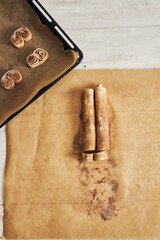Top view of raw chocolate cinnamon rolls on a parchment paper and a sheet pan on the table