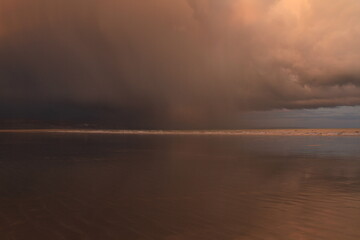 Storm Cloud Moves across the Beach at Black Rock sands, producing a dramatic sky,with orange grey clouds producing an eerie scene