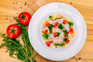 spaghetti with salmon, broccoli and tomatoes in a creamy sauce on a decorated table