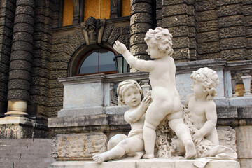 Vienna. Austria. 29 February 2020. Neue Burg Art Historical Museum steps decorated by Kids sculptures in Vienna at coudy summer day. Stone figures of three young children playing.