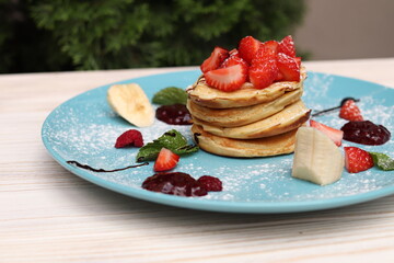 Pancakes with strawberries and chocolate in a cafe, delicious sweet breakfast