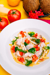 spaghetti with salmon, broccoli and tomatoes in a creamy sauce on a decorated table