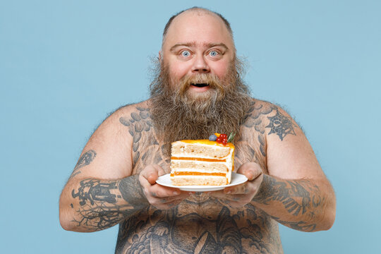 Excited Fat Pudge Obese Chubby Overweight Man Has Tattooed Naked Bare Big Belly Hold Sweet Pastries Cake Isolated On Blue Color Background Studio Portrait. Weight Loss Obesity Unhealthy Diet Concept.