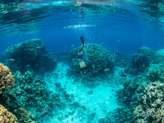 Fototapeta na wymiar Young man dive at coral reef in tropical sea