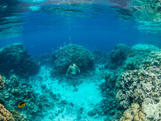 Young man dive at coral reef in tropical sea
