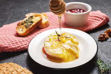 Delicious beautiful baked camembert with honey, walnuts, herbs and cranberries