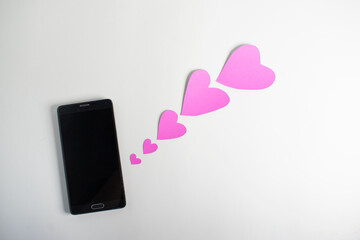 Smartphone and hearts paper on
 White background. Valentine or Sending love through social networks.