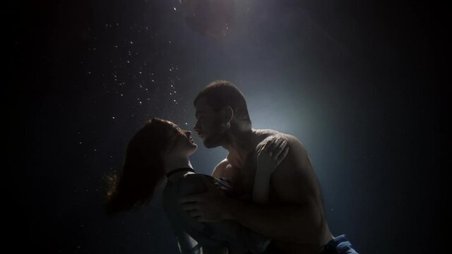 handsome man is embracing his girlfriend underwater, love and passion of loving couple