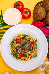 Fetuccini with fried meat and tomatoes on a decorated table