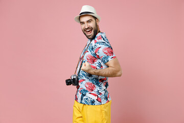 Happy traveler tourist man in hat photo camera doing winner gesture celebrating clenching fists say yes isolated on pink background. Passenger traveling abroad on weekends. Air flight journey concept.