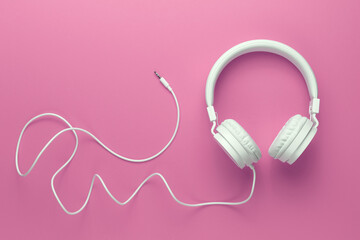 Modern white headphone on pink background. Music concept.