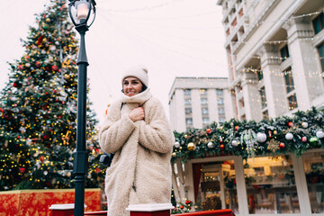 Smiling woman standing near Christmas tree in park