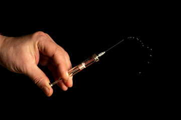 Naklejka premium Medical syringe in man hand on black isolated background closeup