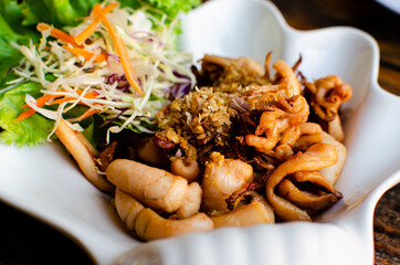 Deep fried sundries squid with garlic and salad in white bowl