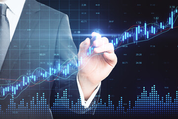 Businessman hand drawing glowing candlestick chart