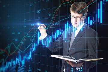 Businessman with book drawing glowing candlestick chart