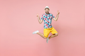 Obraz premium Full length of excited traveler tourist man in summer clothes hat jumping showing victory sign isolated on pink background. Passenger traveling abroad on weekends getaway. Air flight journey concept.