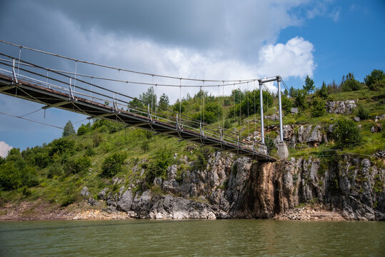 View of a hanging cable strayed suspension wooden bridge, betwen meanders on river Uvac, Serbia. Low angle, shot from river.