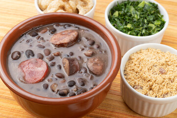 Traditional brazilian feijoada with orange, kale and manioc flour