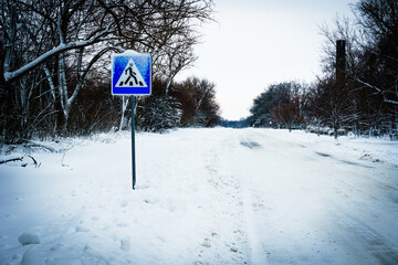 Pedestrian crossing sign in ice. The sign is located on a country road in winter
