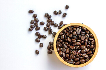 Organic arabica roasted brown coffee beans in a wooden bowl on white background. Concept of fresh aroma caffeine