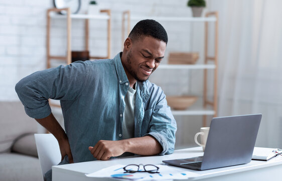 African Guy Having Backache Massaging Aching Back At Workplace Indoor