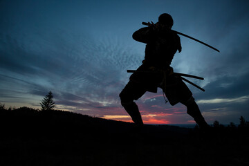 Fototapeta na wymiar Silhouette of a Japanesesamurai with sword training during sunset