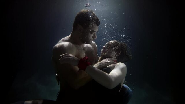 handsome man is hugging sexy woman in depth of swimming pool, lovers underwater, passion and love