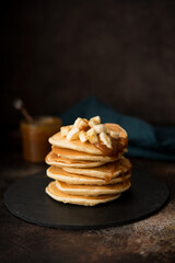American pancakes with caramel and banana on a dark background