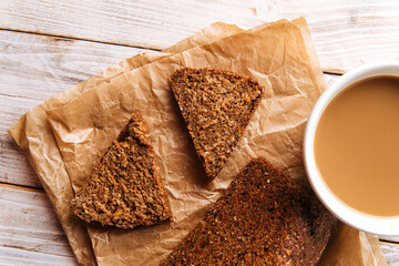 Top view on sliced triangle flourless diet grain bread with coffee on parchment paper