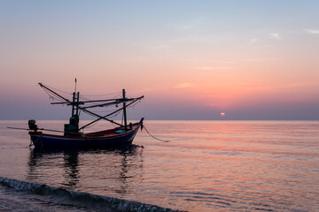 Sunrise on the sea beach with fishing boat
