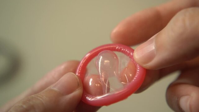 Hands holding pink male condom