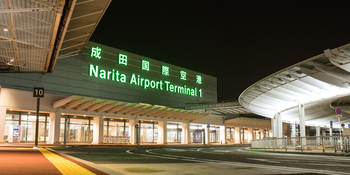Chiba, Japan - November 13, 2020: Exterior of Narita International Airport Terminal 1 with illuminated logo sign at night.