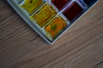 Watercolor paints on a wooden table. Paints background.