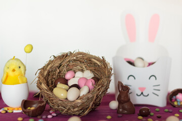 Bird nest with easter almond eggs, chocolate bunny missing a bite, treat box with almods and decorative chick