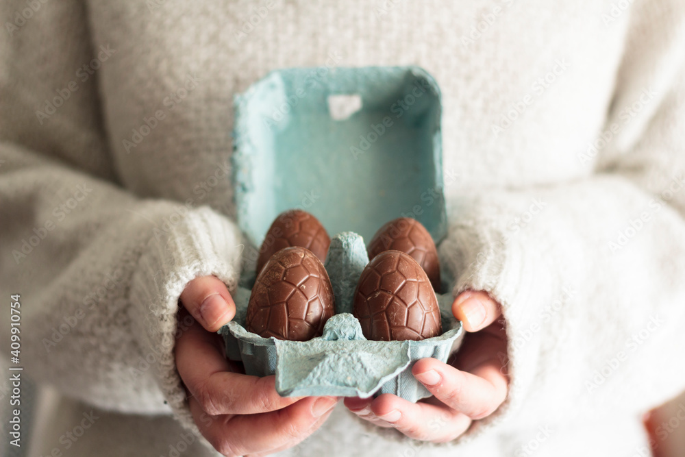 Wall mural Close up of woman holding carton egg box with easter chocolate eggs